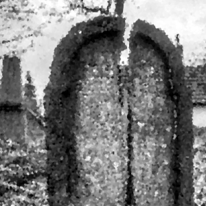 A low resolution photograph of a gravestone with a large crack in it